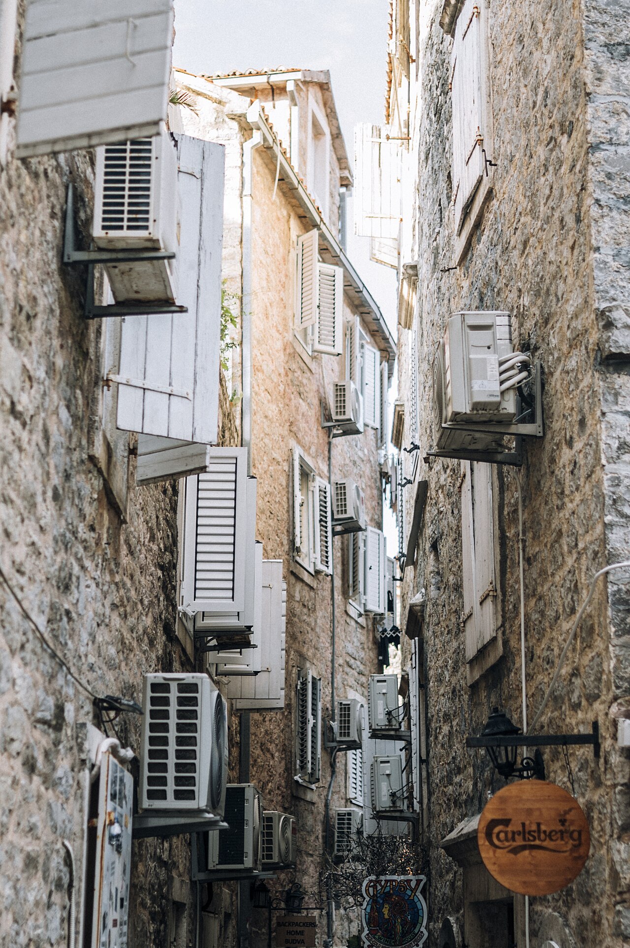 Narrow street lined with air conditioning units in Budva old town with stone buildings