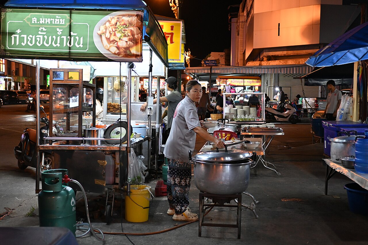 DFC 3510 A street vendor prepares food at a bustling night market stall steam rising from