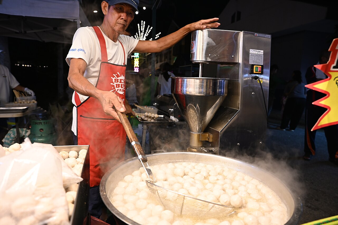 DFC 4474 A street vendor scoops steaming fish balls from a large boiling pot at a night ma